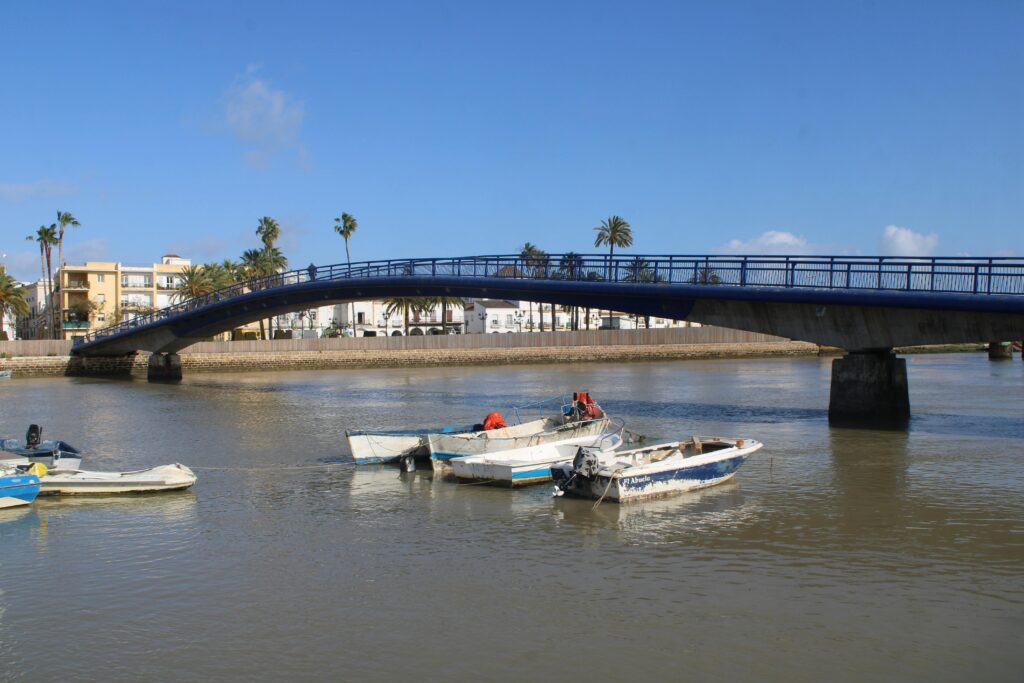 Charming river scene with boats and bridge in El Puerto de Santa María, Spain.